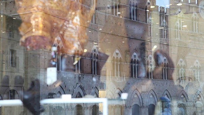 Wedding videographer Tuscany: A view of Palazzo pubblico, reflected in a shop window in piazza del Campo.